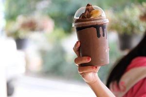 Hand holding a cup of iced cocoa, coffee, cocoa, brownies, stylish coffee shop photo