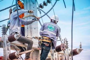 Electricians are climbing on electric poles to install and repair power lines, Some technicians do not wear helmets. may be dangerous photo