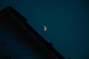 la noche en el pueblo ucraniano se ve exactamente así. con luna brillante y clara y casas de campo debajo foto