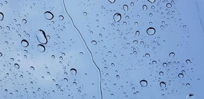 Water droplets perspective through window glass surface against blue sky good for multimedia content photo