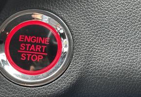 car engine start stop button on dark leather background. copy space photo