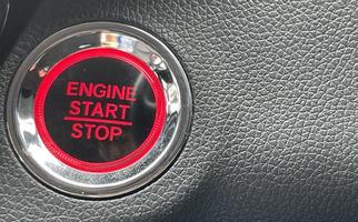 car engine start stop button on dark leather background. copy space photo