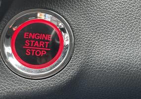 car engine start stop button on dark leather background. copy space photo