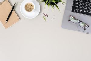 Flat lay office desk table with laptop, notebook, eyeglasses and cup of coffee. Workspace with copy space photo