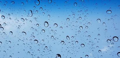 Water droplets perspective through window glass surface against blue sky good for multimedia content photo