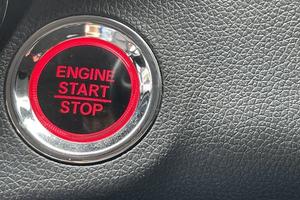 car engine start stop button on dark leather background. copy space photo