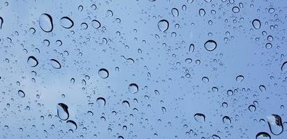 Water droplets perspective through window glass surface against blue sky good for multimedia content photo