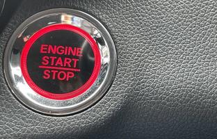 car engine start stop button on dark leather background. copy space photo