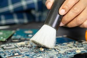 Technician use brush and air blower ball to clean dust in circuit board computer. Repair upgrade and maintenance technology. photo