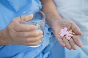 Asian senior elderly old lady woman holding Vitamin pills drug in her hand, healthy strong medical concept. photo