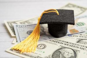 sombrero de la brecha de graduación en el dinero de los billetes en dólares estadounidenses, concepto de enseñanza de aprendizaje de la tarifa de estudio de educación. foto