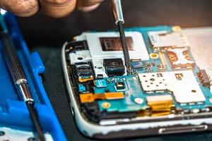 técnico que repara el interior del teléfono móvil con un soldador. circuito integrado. el concepto de datos, hardware, tecnología.