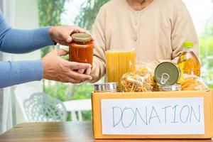 voluntarios poniendo varios alimentos secos en cajas de donación para ayudar a las personas. foto