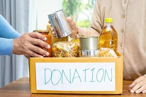 voluntarios poniendo varios alimentos secos en cajas de donación para ayudar a las personas. foto