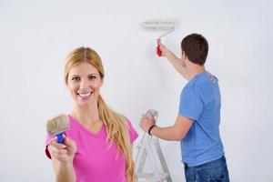 pareja feliz pintando una pared en su nuevo hogar foto