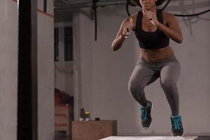 black woman is performing box jumps at gym photo