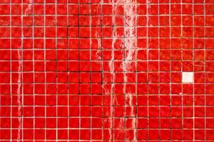 pequeñas baldosas cerámicas rojas sucias en la fachada del edificio, superficie de pared de mosaico retro, textura y patrón grunge, fondo. foto
