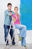 pareja feliz pintando una pared en su nuevo hogar foto