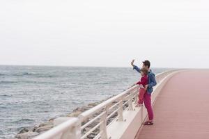 madre y niña linda en el paseo marítimo junto al mar foto