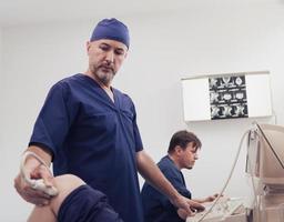 doctor working at the hospital operating ultrasound scanning machine examining knee of her female patient technology modern medicine people vitality concept. photo