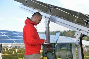 engineer using laptop at solar panels plant field photo