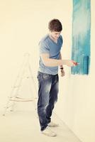handsome young man paint white wall in color photo