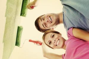 pareja feliz pintando una pared en su nuevo hogar foto