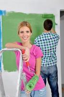 pareja feliz pintando una pared en su nuevo hogar foto