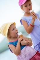 little girls eating ice cream by the sea photo