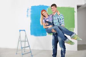 pareja feliz pintando una pared en su nuevo hogar foto