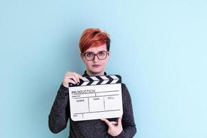 woman holding movie clapper against cyan background photo