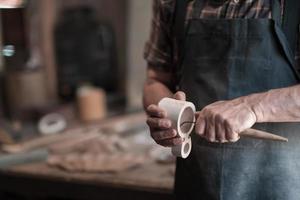 Manos tallando copa de madera, trabajando con cincel de cerca. taller de madera. proceso de fabricación de utensilios de cocina de madera foto