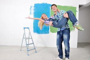 pareja feliz pintando una pared en su nuevo hogar foto