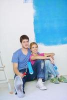 pareja joven feliz relajándose después de pintar en un nuevo hogar foto