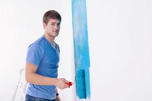 handsome young man paint white wall in color photo