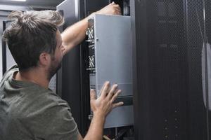 IT engineer working In the server room or data center The technician puts in a rack a new server of corporate business mainframe supercomputer or cryptocurrency mining farm. photo