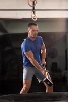 man workout with hammer and tractor tire photo