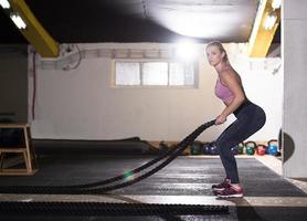 athlete woman doing battle ropes cross fitness exercise photo