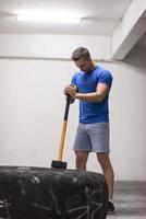 entrenamiento de hombre con martillo y neumático de tractor foto