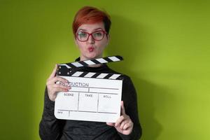 redhead woman holding movie  clapper on green background photo
