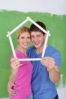 pareja feliz pintando una pared en su nuevo hogar foto