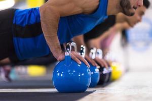 young athletes doing pushups with kettlebells photo