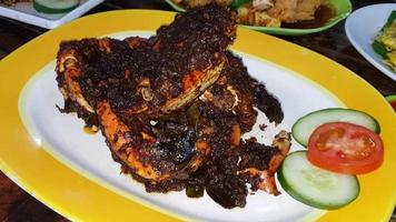 delicioso plato de cangrejo de marisco indonesio cocinado con especias y salsa de condimento envuelto en un plato de hoja de plátano con otros platos de fondo en un restaurante indonesio almacen de video