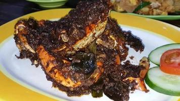 Delicious Indonesian seafood crab dish cooked with spices and seasoning sauce wrapped in banana leaf plate with other background dishes in Indonesian restaurant stock video