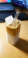 refreshing drink Ice Dalgona Coffee a trendy fluffy frothy creamy whipped coffee served in a korean square glass photo