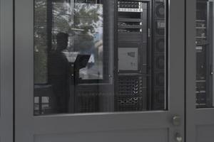 Software Engineer Working on a Laptop Computer in a Modern Server room. Monitoring Room Big Data Scientist in reflection of the entrance door. photo
