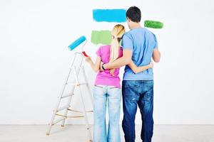 happy couple paint wall at new home photo