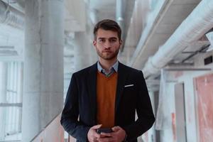 businessman architect using a smartphone while overseeing the construction site photo