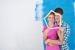 pareja feliz pintando una pared en su nuevo hogar foto