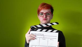redhead woman holding movie  clapper on green background photo
